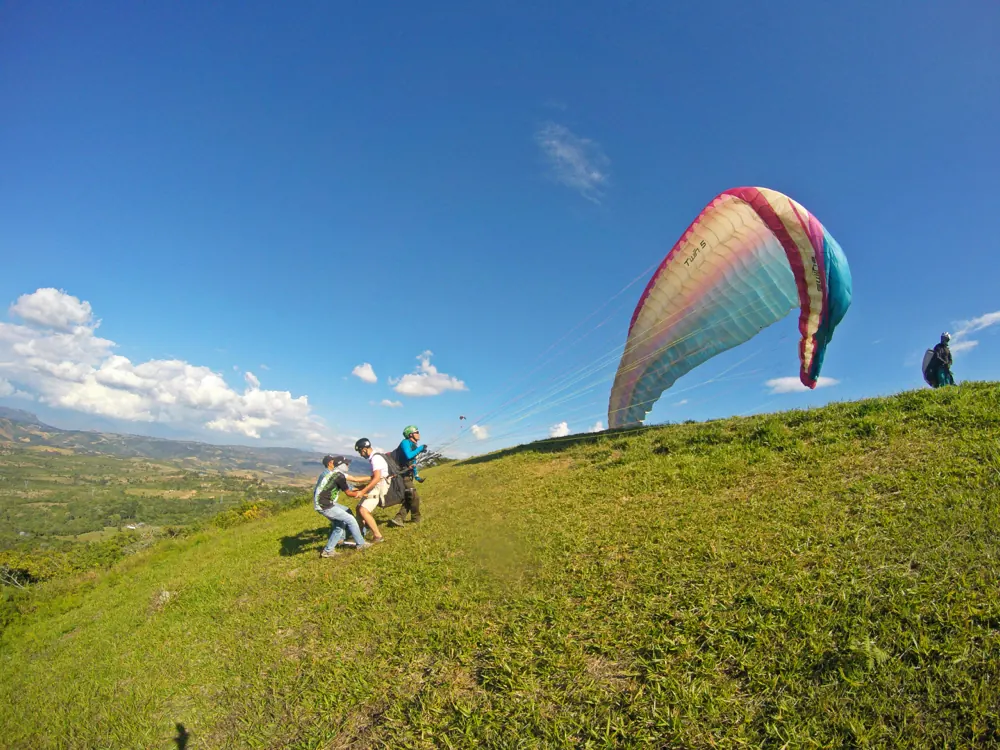 Despegue de parapente con vela de colores en la loma de Curití