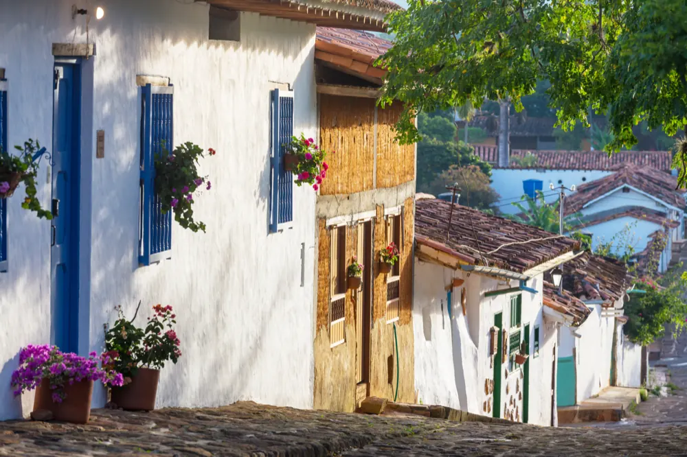 Calle empedrada de Barichara con casas blancas y flores