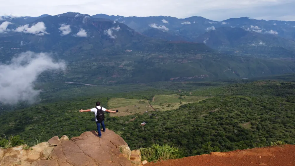 Persona con los brazos abiertos en un peñasco sobre el Cañón del Chicamocha