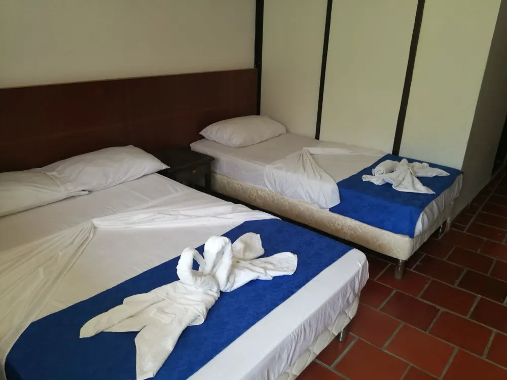 Habitación del hotel con tres camas individuales y toallas dobladas