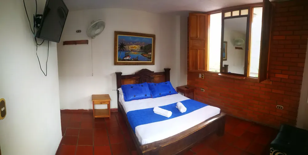 Habitación standard con cama doble, televisor y piso de barro