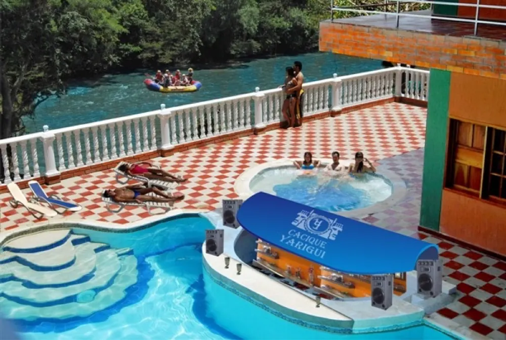Terraza con jacuzzi y piscina del hotel sobre el río Fonce, con una balsa de rafting al fondo