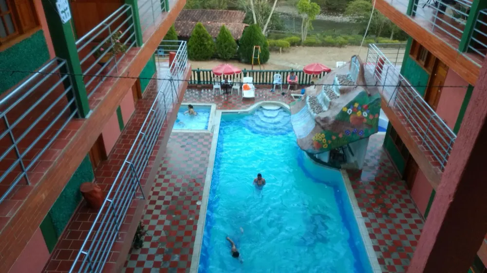 Piscina del hotel vista desde arriba, con tobogán y roca artificial