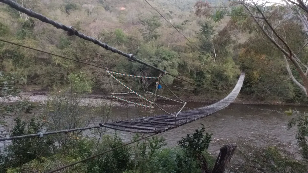 Puente colgante peatonal sobre el río Fonce visto desde la orilla