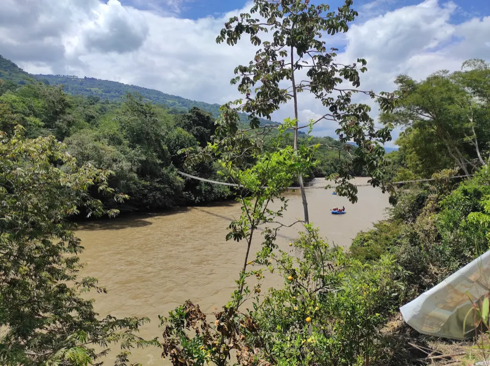 El río Fonce visto desde el hotel, con el puente colgante y una balsa de rafting